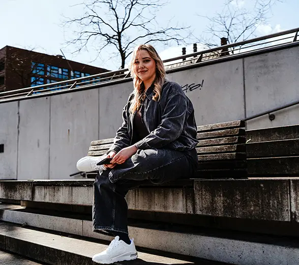 Celine Möller sitzt auf einer Betontreppe in der Stadt
